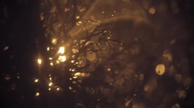 Ilık bir parıltıyla aydınlatılmış soyut organik şekillerin yer aldığı loş bir sahne..