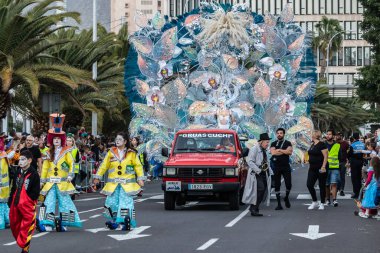 SANTA CRUZ DE TENERIFE, SPAIN - FEBRUARY 21, 2023: Around the Coso parade - along the Avenida de Anaga, official end of Carnival. Amazing warm evening, joyful people in carnival costumes have fun.
