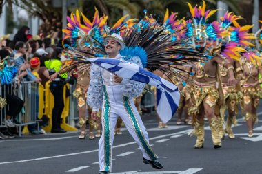 SANTA CRUZ DE TENERIFE, SPAIN - FEBRUARY 21, 2023: Around the Coso parade - along the Avenida de Anaga, official end of Carnival. Amazing warm evening, joyful people in carnival costumes have fun.