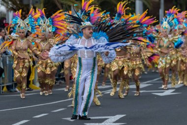 SANTA CRUZ DE TENERIFE, SPAIN - FEBRUARY 21, 2023: Around the Coso parade - along the Avenida de Anaga, official end of Carnival. Amazing warm evening, joyful people in carnival costumes have fun.