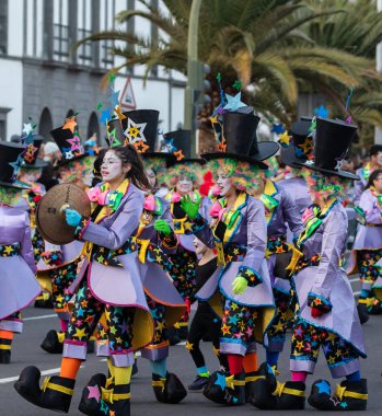 SANTA CRUZ DE TENERIFE, SPAIN - FEBRUARY 21, 2023: Around the Coso parade - along the Avenida de Anaga, official end of Carnival. Amazing warm evening, joyful people in carnival costumes have fun.