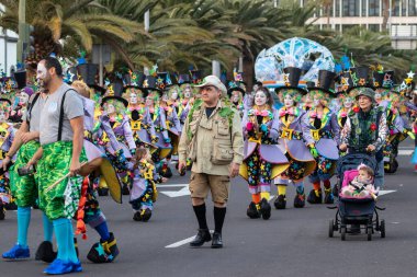 SANTA CRUZ DE TENERIFE, SPAIN - FEBRUARY 21, 2023: Around the Coso parade - along the Avenida de Anaga, official end of Carnival. Amazing warm evening, joyful people in carnival costumes have fun.