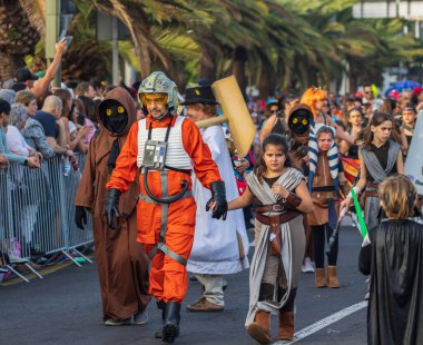 Santa CRUZ DE TENERIFE, İspanya - 13 Şubat 2024: The Coso geçidi, Cavalcada - Avenida de Anaga boyunca, Karnaval 'ın resmi sonu. İnanılmaz sıcak bir akşam, karnaval kostümlü neşeli insanlar eğleniyor..