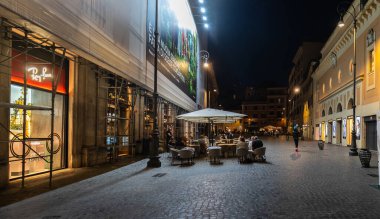 ROME, ITALY - 24 Mayıs 2022: Roma 'da bir yerleşim yeri, insanların geceleri eski bir kaldırım taşı caddesinde küçük bir mahalle restoranında yemek yedikleri yer..