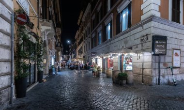 ROME, ITALY - 24 Mayıs 2022: Roma 'da bir yerleşim yeri, insanların geceleri eski bir kaldırım taşı caddesinde küçük bir mahalle restoranında yemek yedikleri yer..