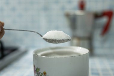 Close up view of a spoon full of rafined white sugar, hyperglycemia health care concept. 