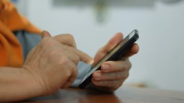 İletişim kurmak için akıllı telefon kullanan yaşlı bir kadının elini sıkmak, sağlık hizmetleri ve teknoloji yaşam tarzı. 4K