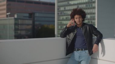 Moda dünyasından genç bir adam şehrin yukarısında telefonla konuşuyor.