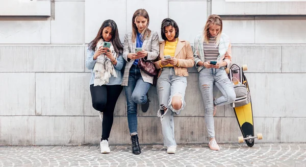 Покоління Багатоетнічних Дівчат Друзів Використовуючи Мобільний Телефон Спирається Стіну Університеті — стокове фото