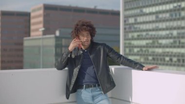young casual attractive man talking on cell phone outdoors between skyscrapers in a beautiful sunlight