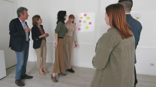 利用现代办公环境中白板上的粘贴便条参与战略规划会议的各类专业人员 — 图库视频影像