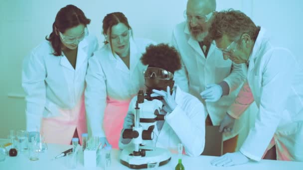 非洲大学生在实验室被同行和教授包围时 在显微镜下分析样本 — 图库视频影像