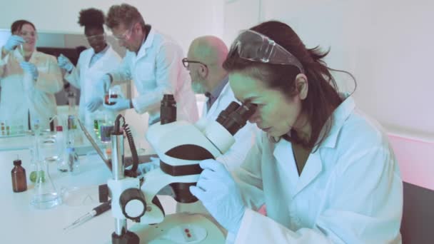 Japansk Forskare Med Mikroskop Ett Mångkulturellt Laboratorium Fokus Engagemang Vetenskaplig — Stockvideo