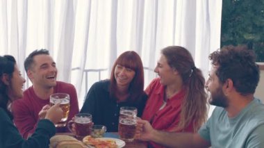 Beş arkadaş grubu, üç kadın ve iki erkek, birlikte keyifli ve rahat vakit geçiriyorlar, bir masanın etrafında oturuyorlar, ellerinde bira kupaları, ve içten bir kahkahayı paylaşıyorlar.
