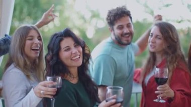 Neşeli Nesil Z dostları dans ediyor ve kırmızı şarap içiyor çatıdaki barbekü partisini gün ışığında kutluyorlar. Heyecanlı gençler yaz tatilinde dans edip dışarıda eğleniyorlar.