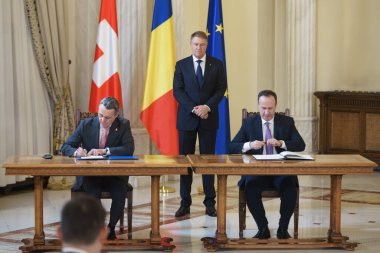 Bükreş, Romanya - 12 Aralık 2022: İsviçre Cumhurbaşkanı Ignazio Cassis (L) ve Romanya maliye bakanı Adrian Caciu (R) bir mali çerçeve anlaşması belgesi imzaladılar.