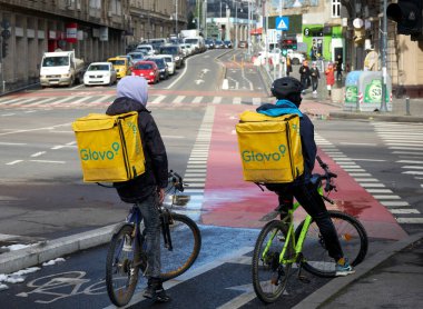 Bükreş, Romanya - 01 Şubat 2023: Romanya 'nın Bükreş kentinde iki Glovo gıda dağıtım kuryesi gıda dağıtımı yapıyor.