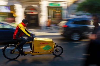 Bükreş, Romanya - 14 Kasım 2023 Bükreş 'te trafikte hız yapan sarı bir DHL DHL kargo bisikleti. Bu resim sadece editörler içindir..