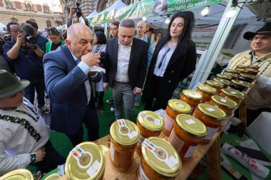 Bucharest, Romania. 29th Mar, 2024: Catalin Cirstoiu, (L) the joint candidate for mayor of Bucharest of the Social Democratic Party (PSD) and the National Liberal Party (PNL), tastes the popular vegetable spread Zacusca during the visit to The Agricu clipart