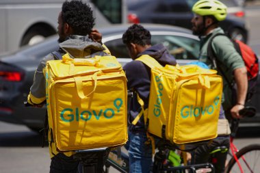 Bucharest, Romania. 21st May, 2024: Two Glovo food delivery couriers, workers of foreign origin, delivers food in Bucharest, Romania.