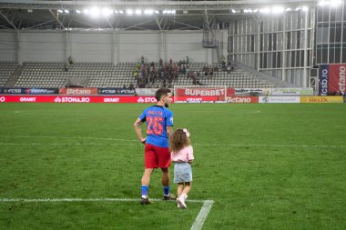 Bükreş, Romanya. 1 Eylül 2024: FCSB 'den Alexandru Baluta, FCSB ve UTA Arad arasında oynanan futbol karşılaşmasının sonunda Romanya 2024-2025 futbol şampiyonasının ilk ligi olan Superliga' nın 8. turunda kızıyla birlikte Arcul de 