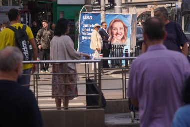 Bucharest, Romania. 13th Sep, 2024: People walk past a tent banner from the presidential election campaign of Elena Lasconi, the President of the Save Romania Union (USR). clipart