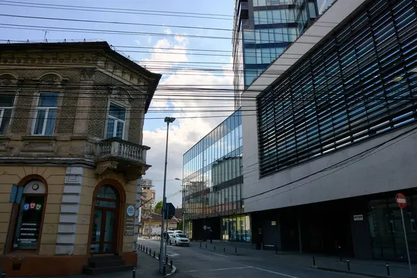 stock image Cluj-Napoca, Romania. 27th Apr, 2024: Architectural juxtaposition between old and new with a beautiful one-story house on the left and Cluj-Napoca Central Business Plaza on the right.