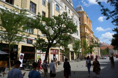 Cluj-Napoca, Romanya. 29 Haziran 2024: Eski Cluj-Napoca kasabasındaki Universitatii caddesi boyunca soldaki manzara: Sebestyen Sarayı, 1923-1933 yılları arasında inşa edildi ve Piarist Kilisesi 1724 yılında inşa edildi..