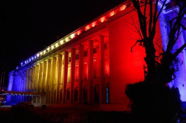 Bükreş, Romanya. 1 Aralık 2024: Romanya Hükümeti 'nin merkezi olan Victoria Sarayı, Romanya Ulusal Günü münasebetiyle Romen bayrağının renkleriyle aydınlatıldı.