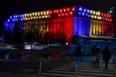 Bükreş, Romanya. 1 Aralık 2024: Romanya Hükümeti 'nin merkezi olan Victoria Sarayı, Romanya Ulusal Günü münasebetiyle Romen bayrağının renkleriyle aydınlatıldı.