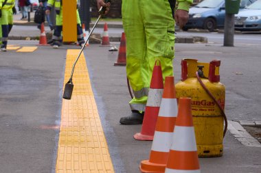 Bucharest, Romania. 4th Dec, 2024: Workers install tactile paving strips to create a pathway for the visually impaired at the exit of the Victoriei subway station in Bucharest. clipart