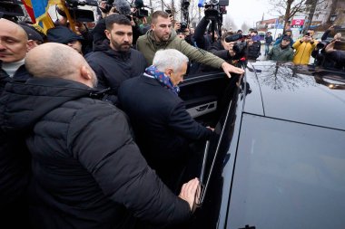 Mogosoaia, Romanya. 8 Aralık 2024: Romanya cumhurbaşkanlığı ikinci tur adayı Calin Georgescu (C), seçimlerin yasal olarak geçersiz sayılmasının ardından kapalı bir sandık merkezinden ayrıldı.