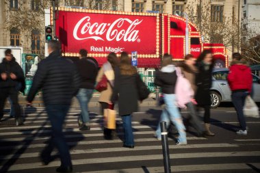 Bükreş, Romanya. 16 Aralık 2024: Bükreş 'te bir sokakta Coca-Cola kamyon şeklinde bir reklamın önünden geçen insanlar