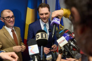Bükreş, Romanya. 17 Aralık 2024: Romanya Enerji Bakanı Sebastian Burduja (R), gazeteciler mikrofonlarını bakanlık genel merkezinde kurarken basın toplantısı düzenlemeye hazırlanıyor.