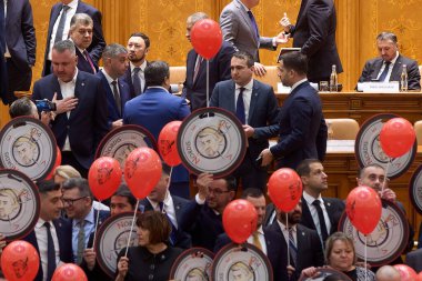 Bükreş, Romanya. 28 Şubat 2025: AUR milletvekilleri hükümete karşı yapılan güven oylamasında Başbakan Marcel Ciolacu 'yu (sol üstte) Pinokyo olarak tasvir eden pankartlarla protesto ettiler.