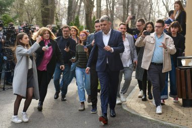Bükreş, Romanya. 12. Mar, 2025: Gazeteciler, PSD Ulusal Siyasi Bürosu toplantısından ayrılırken Sosyal Demokrat Parti (PSD) genel başkanı Marcel Ciolacu 'dan açıklama almaya çalışıyorlar.