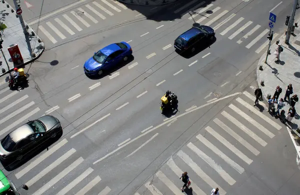 Bükreş, Romanya. 7 Mayıs 2025: Yabancı kökenli Glovo gıda kuryeleri, Romanya 'nın başkenti Bükreş' teki yoğun bir kavşaktan geçerken yiyecek dağıtıyorlar.