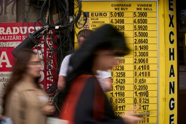 Bükreş, Romanya. 8 Mayıs 2025: Bükreş şehir merkezindeki döviz bürosunda avronun 5.39 ley 'e yükseldiğini gösteren döviz tahtasının önünden geçen insanlar görülüyor.