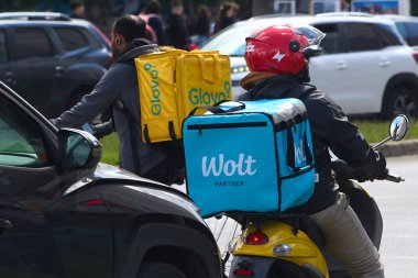Bükreş, Romanya. 13 Mayıs 2025: Glovo ve Wolt gıda dağıtım kuryeleri, yabancı kökenli işçiler, Romanya 'nın Bükreş kentinde gıda dağıtımı yapıyorlar.