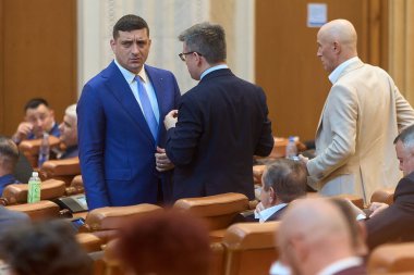 Bükreş, Romanya. 2 Haziran 2025: Rumen Birliği İttifakı (AUR) başkanı George Simion (L), Romanya Parlamentosu 'nda düzenlenen genel kurul toplantısında Mihail Neamtu (C) ve Mugur Mihaescu (R) ile konuştu..
