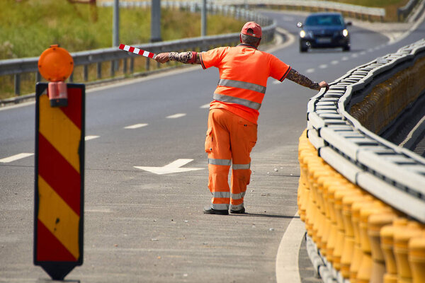 Брагадиру, Румыния. 30 июня, 2025: Рабочий перенаправляет движение, чтобы заблокировать развязку, соединяющую дорогу Бухарест-Александрия с участком Бухарестской автомагистрали (А0) между Брагадиру и Джойтой, которая вот-вот откроется в ближайшие часы.