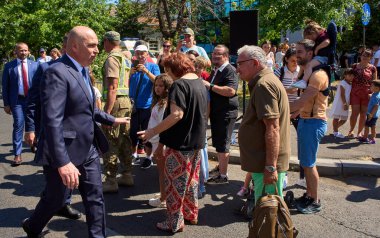 Bükreş, Romanya. 20 Temmuz 2025: Romanya Başbakanı Ilie Bolojan (L) Bükreş 'te düzenlenen Romanya Havacılık ve Hava Kuvvetleri Günü kutlamasından ayrılırken halk tezahürat yapıyor.