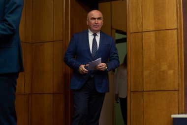 Bükreş, Romanya. 22 Temmuz 2025: Romanya Başbakanı Ilie Bolojan ve Dragos Anastasiu (resimde değil), Başbakan Yardımcısı, devlet şirketlerinin reformu hakkında Romanya Hükümeti Victoria Sarayı 'nda basın toplantısı düzenlediler.