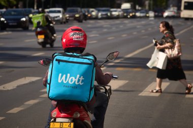 Bükreş, Romanya. 21 Ağustos 2025: Yabancı kökenli işçiler Wolt gıda dağıtım kuryesi Romanya 'nın Bükreş kentinde gıda dağıtımı yapıyor.