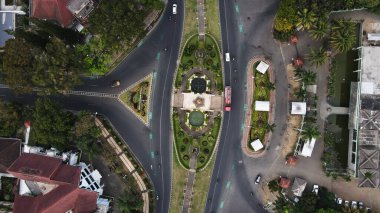 Malang, Indonesia  September 20th, 2024 A drone-captured image of an urban area, with buildings nestled among lush green trees. The cityscape showcases a balance of development and greenery, adding to the charm of the area. clipart