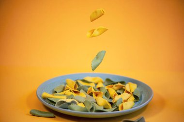 yellow and green pasta with spinach color on a plate on a bright background