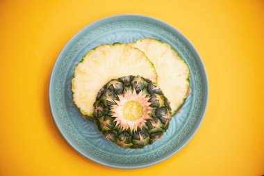 pineapple rings on a plate on a bright yellow background