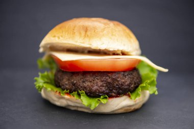 İştah açıcı ev yapımı burger, arka planda sığır eti ve peynir.