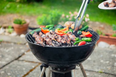 Bahçe ızgarasında sebzelerle barbekü pişir.