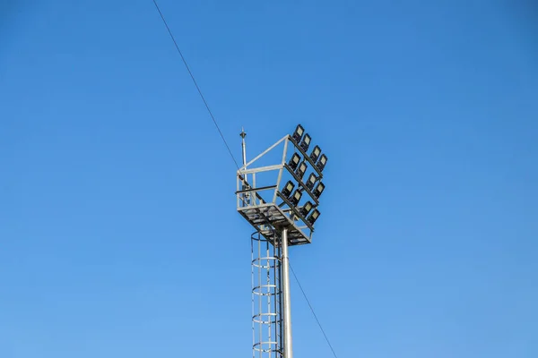 青い空の背景にスポットライトのシルエット スタジアム照明用ランプ — ストック写真